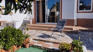 Une terrasse avec une chaise, des plantes en pot et une table.