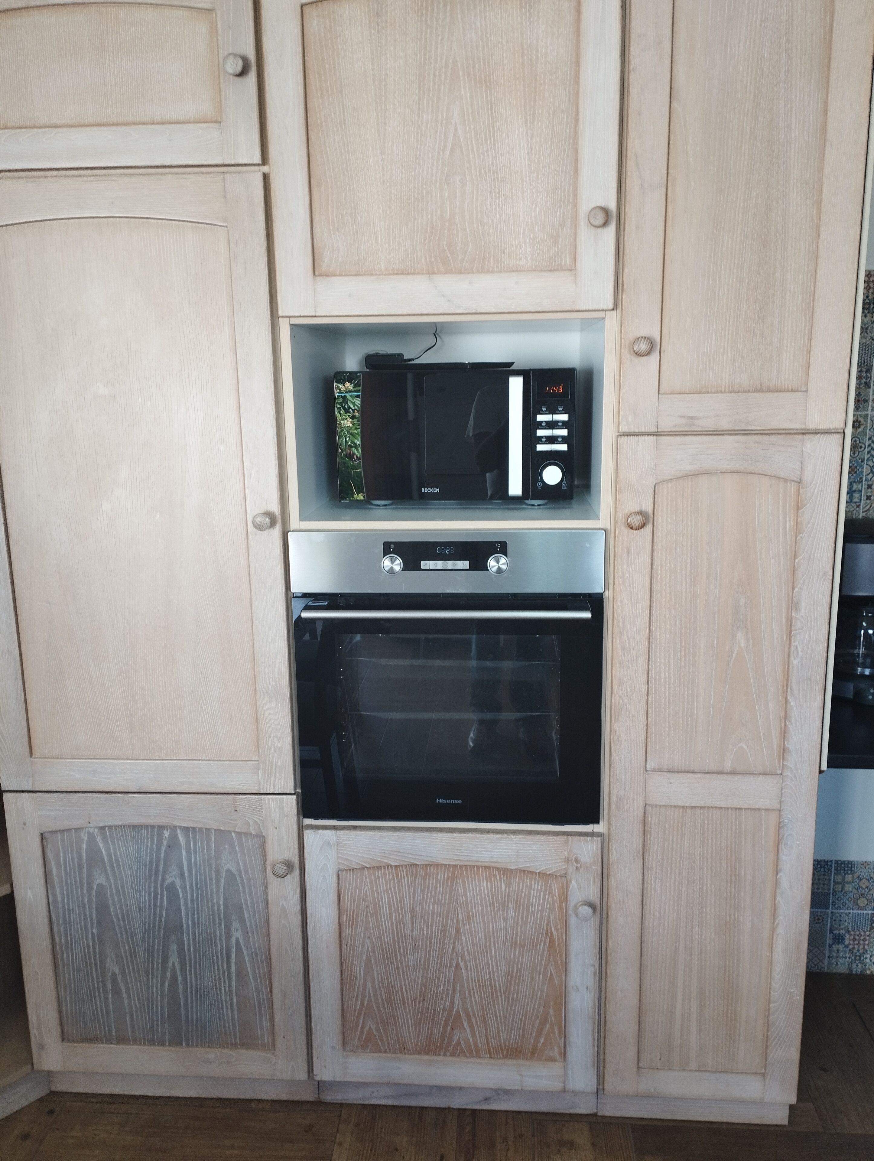 A kitchen with a microwave, oven, and wooden cabinetry.