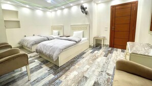 Ein Schlafzimmer mit einem Bett, zwei Nachttischen, einem Sessel, einer Holztür und einem kleinen Tisch mit Marmorplatte.