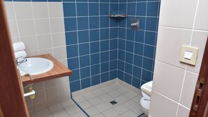 A small bathroom with a sink, toilet, and blue tiled walls. - LE CHANNEL HOTEL (Le Marin)