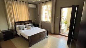 A bedroom with a bed, curtains, a ceiling fan, and a door leading to a balcony. - Cozy & Spacious 3BR Near Beach | Pool & Gym (Dar es Salaam)