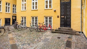 A courtyard with a cobblestone floor, yellow buildings, and bicycles parked in front.