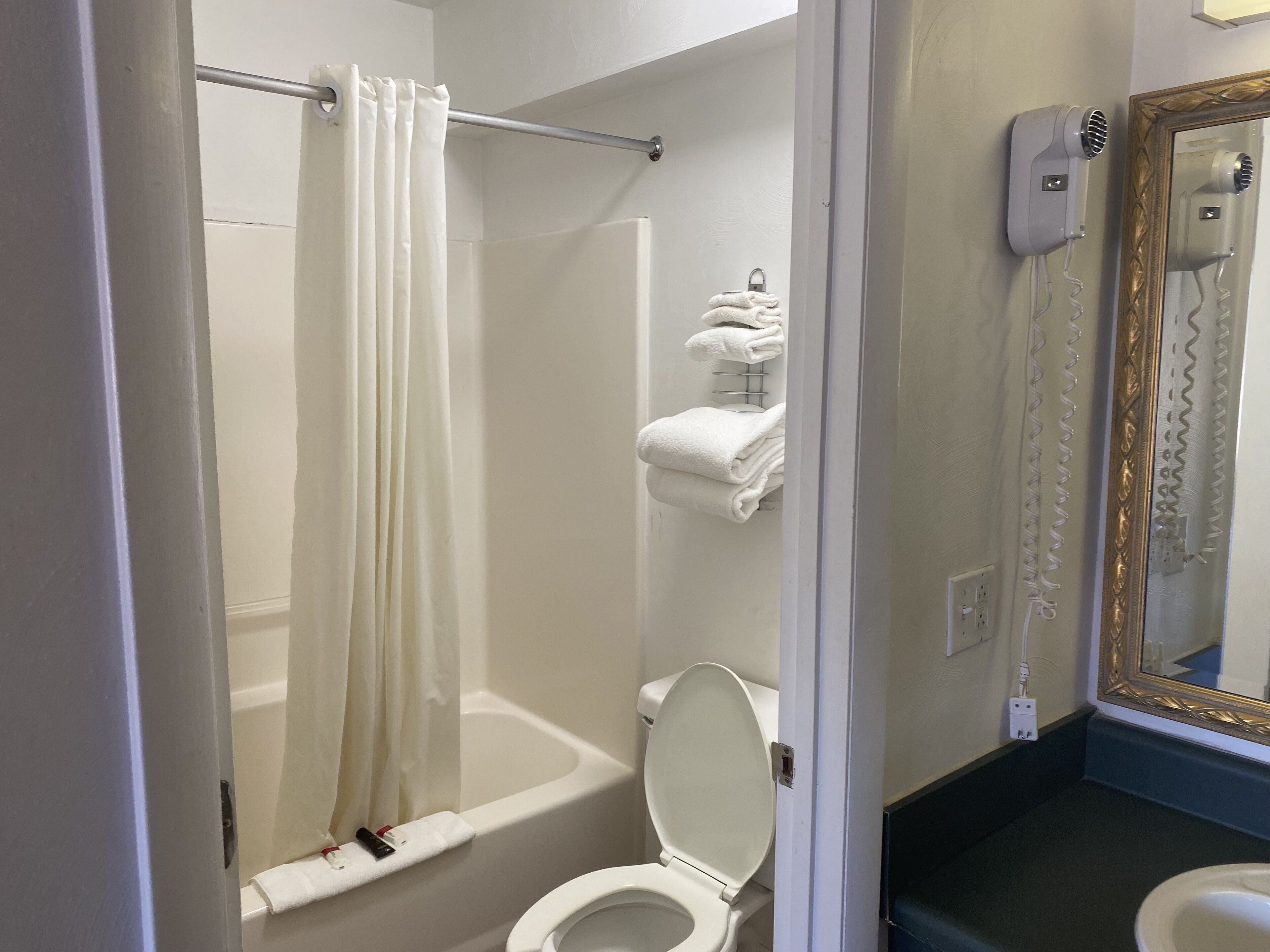 Un baño con bañera, inodoro y toallero con toallas dobladas.