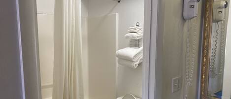 Un baño con bañera, inodoro y toallero con toallas dobladas.