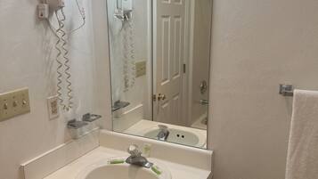 A bathroom with a white sink, a mirror, a hairdryer, and a towel rack.