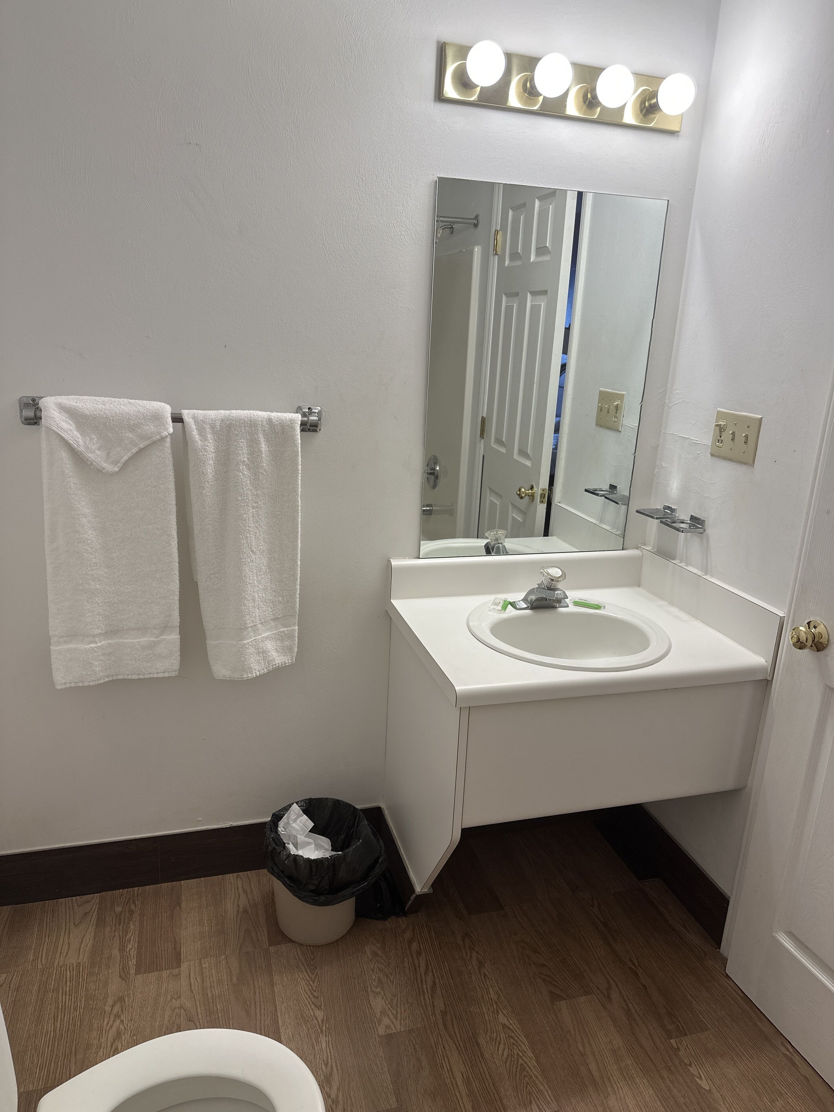 A bathroom with a white sink, mirror, and two towels hanging on a rack.