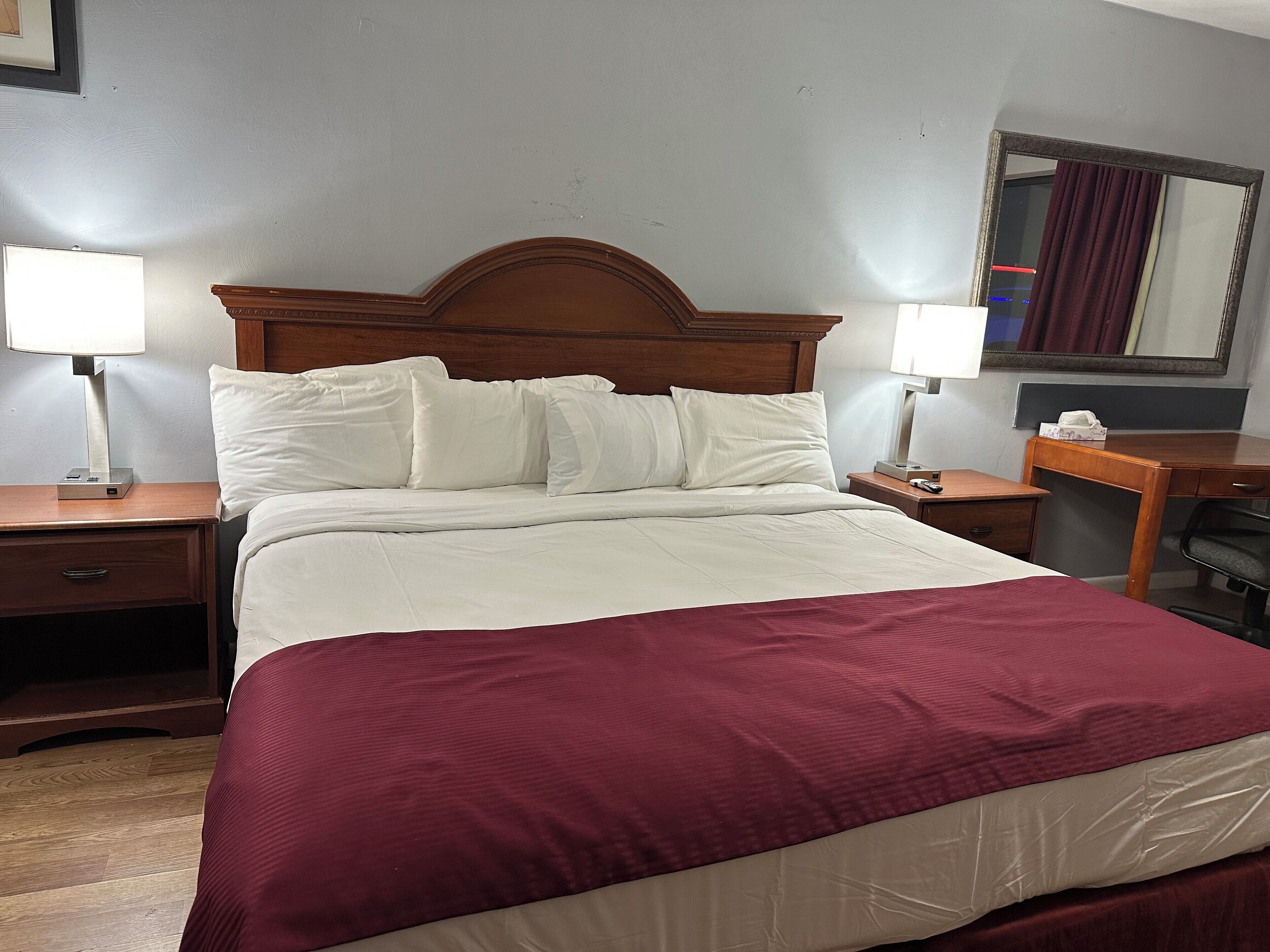 A hotel room with a large bed, two bedside tables, a desk, and a chair.