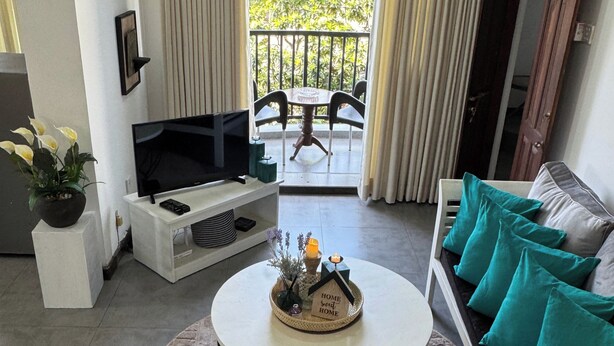 Una sala de estar con televisor, sofá y una mesita con un objeto decorativo.