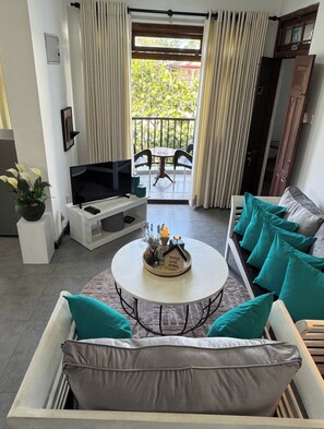 A living room with a TV, sofa, and a small table with a decorative item.