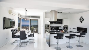 Een moderne keuken met een centraal eiland, barstoelen en een eethoek met uitzicht.