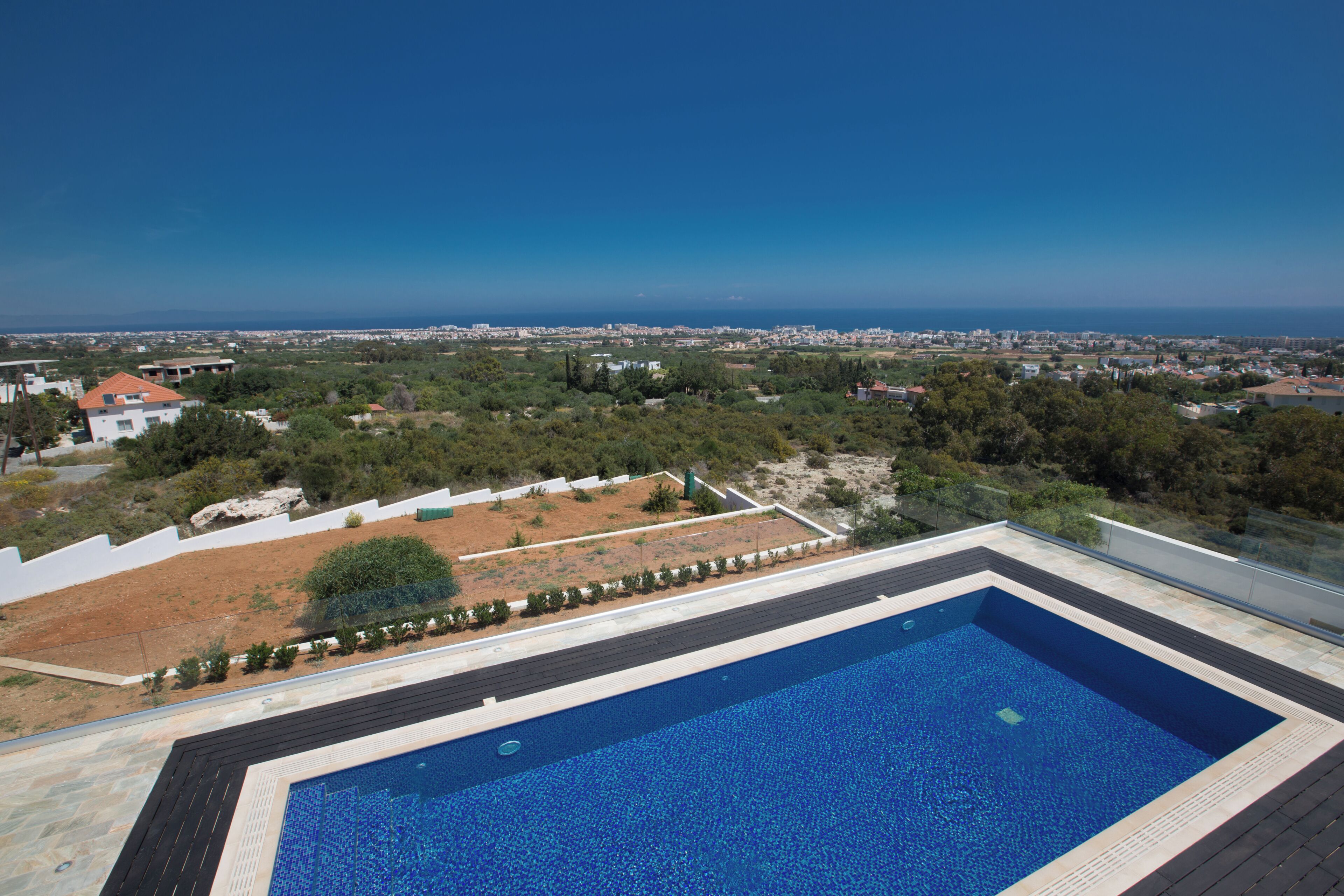 Una piscina rectangular con vistas despejadas del paisaje circundante, incluyendo una ciudad lejana y una masa de agua.