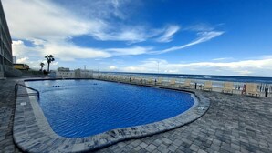 A swimming pool with a view of the ocean and a paved deck area. - Heart of Daytona 1 bedroom w/kitchen, sleeps 4, private balcony, fireplace, pool (Daytona Beach)