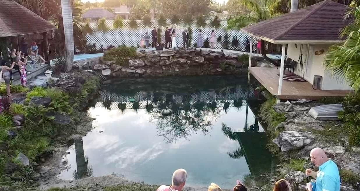 A pool area with a stone structure, lounge chairs, and a covered seating area.