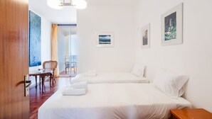 Habitación de hotel con dos camas, una mesa de comedor, una silla y un balcón con vistas.