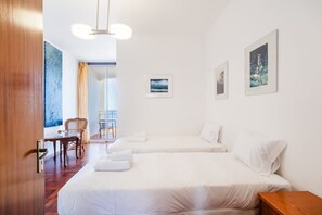 Une chambre d’hôtel avec deux lits, une table à manger, une chaise et un balcon avec vue.