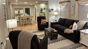A living room with a sofa, armchair, coffee table, and a dining area in the background. - The Landing Zone.
 Comfortable and cozy three bedroom with two car garage.  (East Moline)