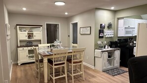 A compact kitchen with white cabinets, a dining table with four chairs, and a small island with a sink. - The Landing Zone.
 Comfortable and cozy three bedroom with two car garage.  (East Moline)