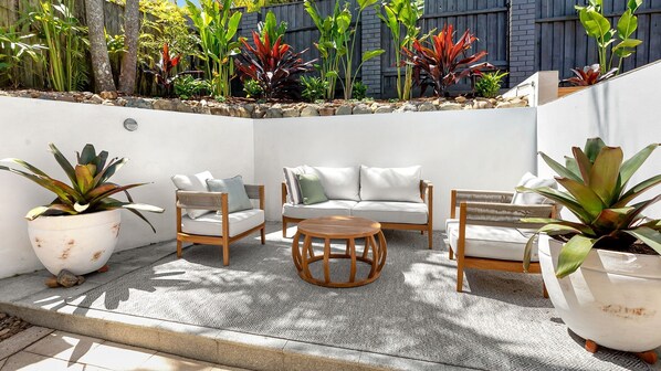An outdoor seating area with a sofa, two chairs, and a round table.