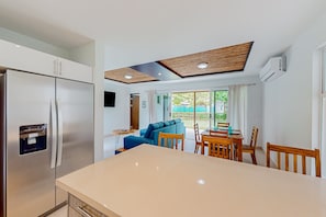 Enjoy meals in the kitchen with a refrigerator and central island, adjacent to a dining area with a wooden table and comfortable seating.