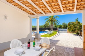 Un espacio de comedor al aire libre con una mesa para dos, una botella de vino y una copa.