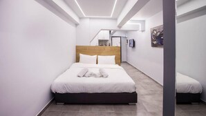 A modern hotel room with a large bed, a wooden headboard, and a small seating area. - Exclusive New Modern Apartment at Syntagma Square (Athens)