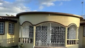 Un bâtiment doté d’une façade incurvée, de grandes fenêtres ornées de grilles métalliques décoratives et d’un toit plat.