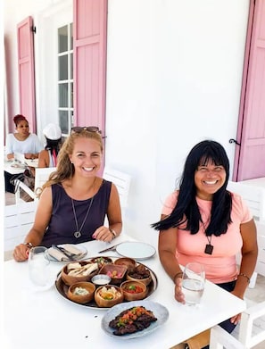 Two women seated at a table with a variety of dishes and drinks.