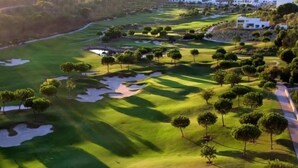 Un campo de golf con búnkeres de arena, árboles y un club de campo.