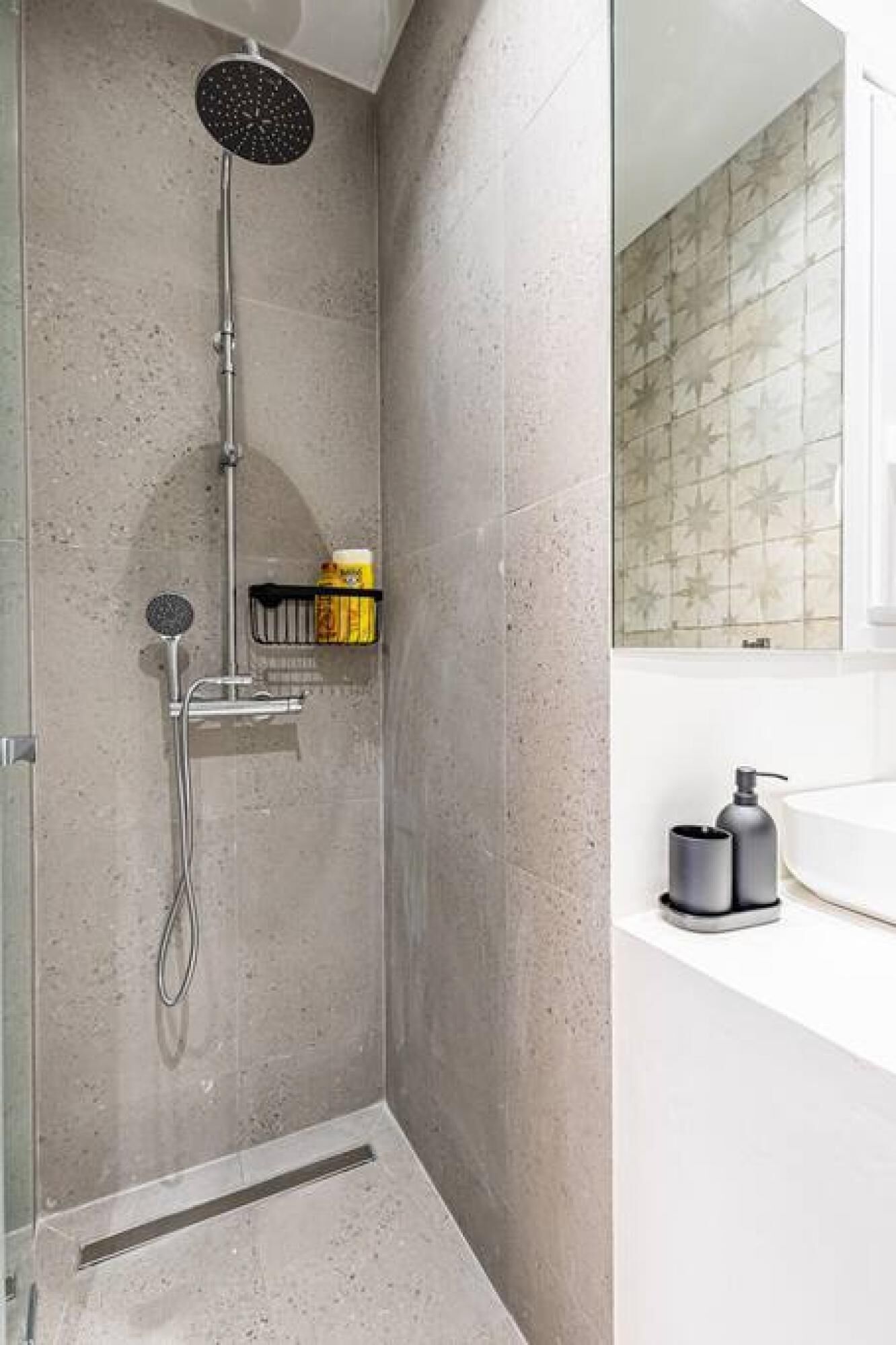 A modern shower with a rain showerhead, a handheld showerhead, and a handheld soap dispenser.