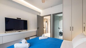 A modern hotel room with a large bed, a flat-screen TV, a wardrobe, and a view of the bathroom. - Philoxenia I Acropolis Museum (Athens)
