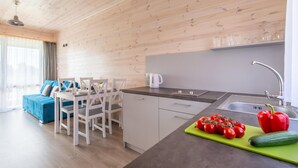 Une cuisine moderne aux murs en bois, un coin repas avec des chaises blanches et un canapé bleu.