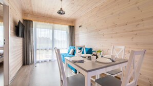 Une pièce chaleureuse avec un décor intérieur en bois, une table à manger dressée avec des assiettes, des tasses et un vase, et un canapé bleu agrémenté de coussins.