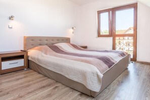 Un dormitorio con cama, mesitas de noche, un ventanal y vistas al exterior.