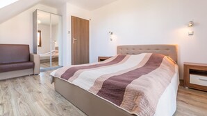 Een slaapkamer met een bed, een bank, een kledingkast en een spiegel.