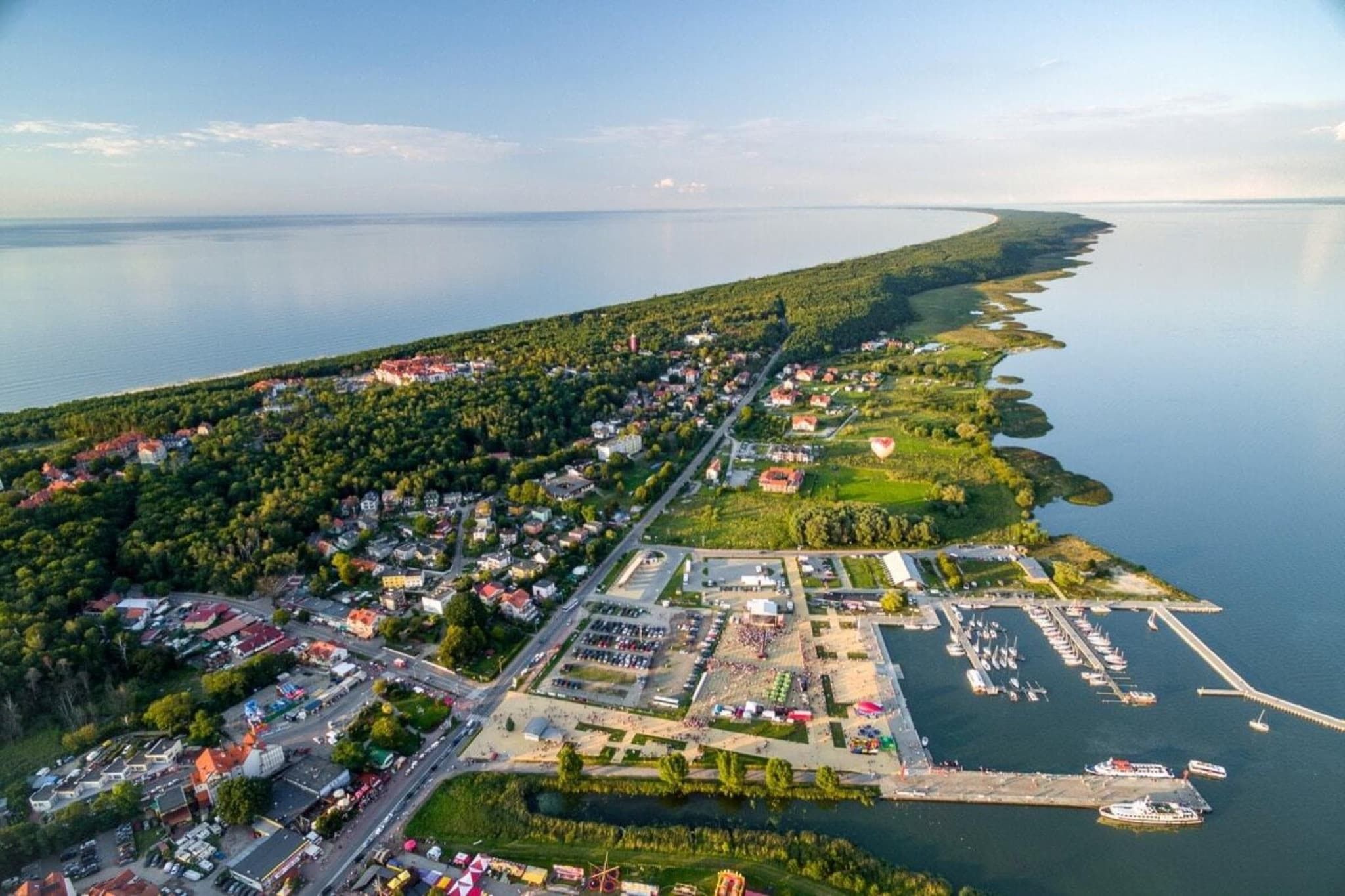 Ett flygbildsfoto av en kuststad med en småbåtshamn, bostadsområden och en stor vattenyta.