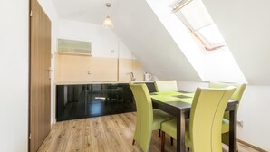 Een moderne keuken met zwarte kastjes, een houten vloer en een eethoek met groene stoelen.