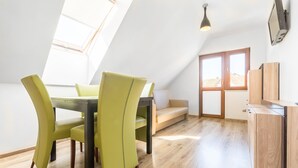 Een eetgedeelte met een tafel en stoelen, een bank, een raam en een houten inbouwkast.