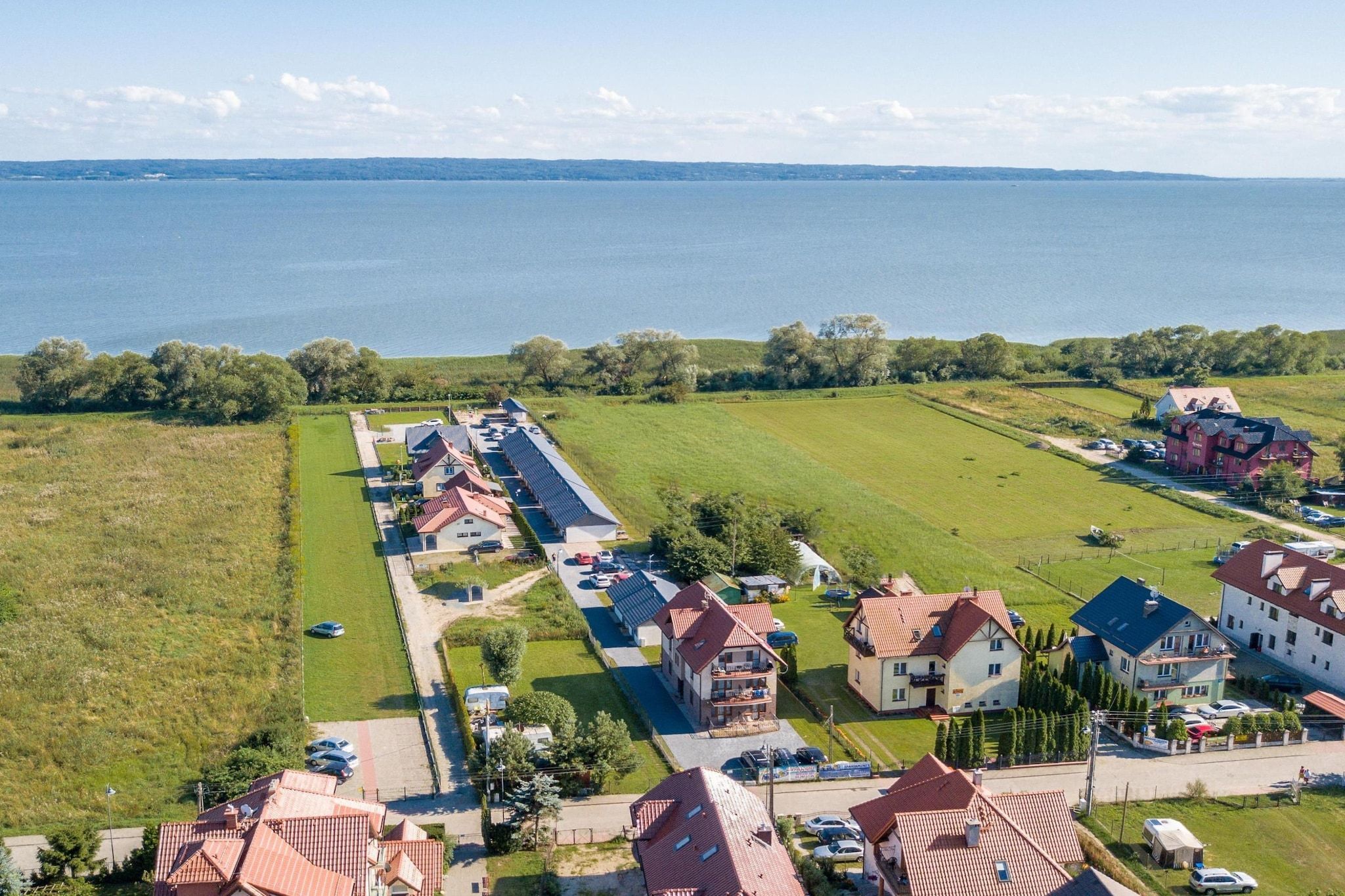 Área residencial com casas, uma estrada e um corpo d'água ao fundo.