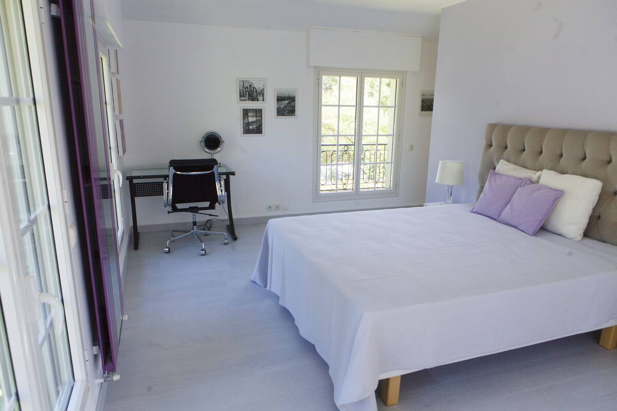 A bedroom with a large bed, a desk, and a window.