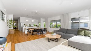 A modern living room with a grey sofa, a round coffee table, and a dining area with a wooden table and chairs.