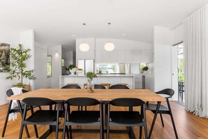 Een moderne keuken met witte kasten, een houten eettafel en zwarte stoelen.