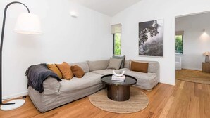 A modern living room with a sectional sofa, a round coffee table, and a floor lamp. - Ukiyo (Cabarita Beach)