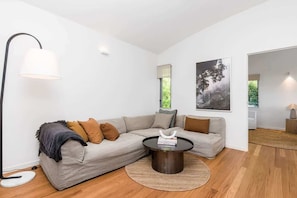 A modern living room with a sectional sofa, a round coffee table, and a floor lamp. - Ukiyo (Cabarita Beach)