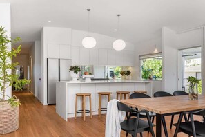 Een moderne keuken met witte kasten, een centraal eiland met krukken en hanglampen.