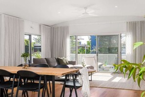 A modern living room with a dining area, large windows, and a balcony.