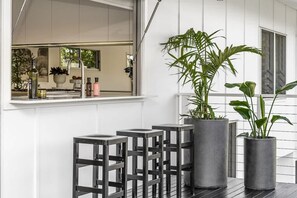 Een moderne keuken met een raam, barstoelen en plantenpotten.
