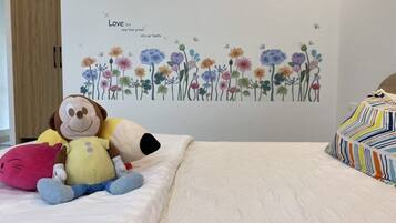 Une chambre avec un lit, un mur orné d’une fresque florale et un jouet en peluche représentant un singe.