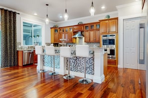 Una cocina moderna con armarios de madera, electrodomésticos de acero inoxidable y una isla central con taburetes de bar.