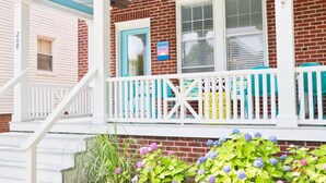 A two-story house with a porch, a mailbox, and a small garden with hydrangeas.