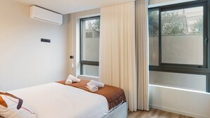 Hotellihuone, jossa on sänky, ikkuna ja ilmastointilaite.